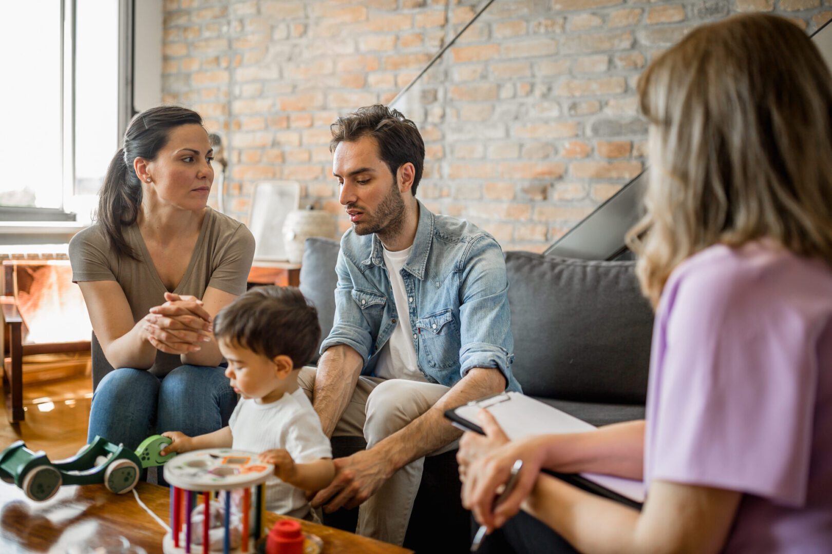 Young couple with a child on a therapy Family discussing with a counselor, toddler playing.