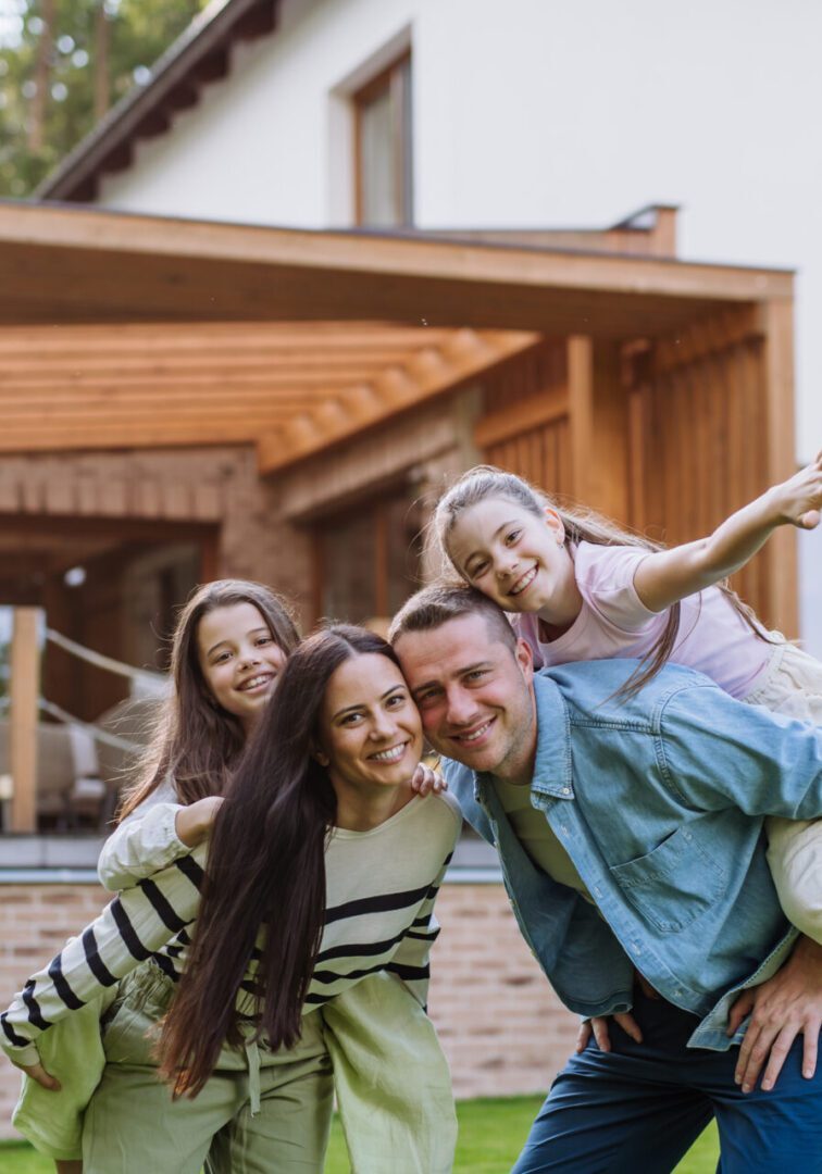 Beautfiul young family standing in front their family home, enjoying together time. Family enjoying time outside modern house.